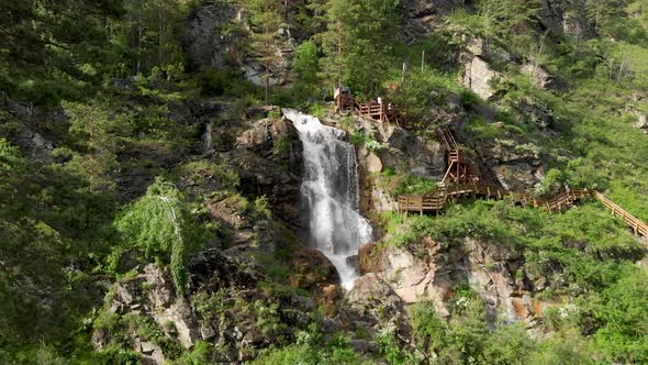 Drone Flying Over a Green Forest with Waterfall in the Altai Mountains.