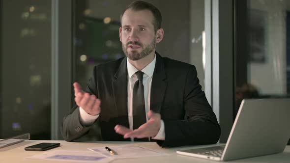 Young Businessman Giving Presentation on Office Table at Night alt