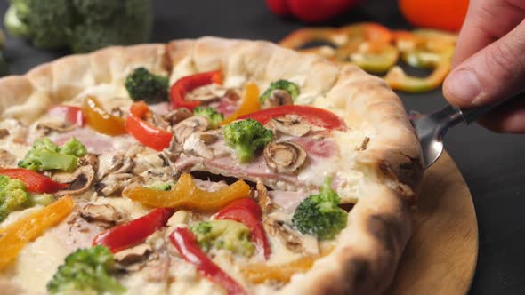 A Male Hand Raises a Slice of Pizza on a Cake Spatula