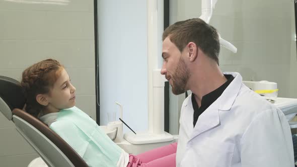 Lovely Dentist Talking with His Young Patient alt