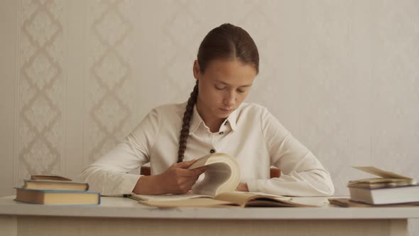 Young woman sits at desk, reading encyclopedia book, turning pages. Library, education study at home