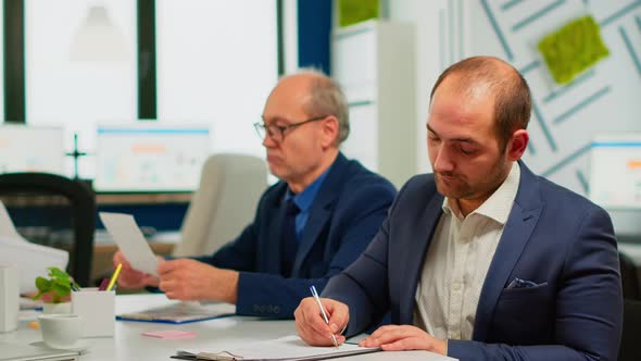 Businessman Reading Paper Document Discussing Contract with Confident Partner alt