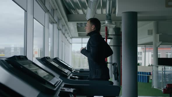 Young man is engaged in crossfit, doing leg exercises, warming up, in the gym. alt