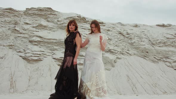 Portrait of Caucasian Beautiful Young Females in White and Black Dresses Back To Back and Smiling To alt