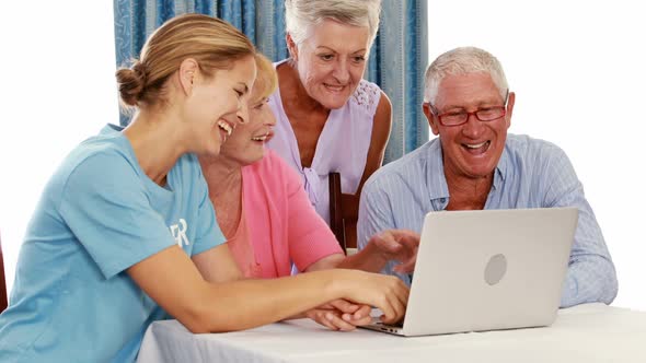 Female volunteer and senior citizens using laptop alt