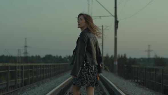 Young Beautiful Rebel Woman with Yellow Flowers Walks Along the Railway alt