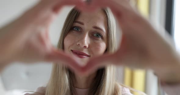 Beautiful Happy Young Caucasian Woman 30s Sharing Love Join Fingers Showing Heart Shape at Camera alt