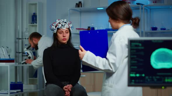 Neuroscience Doctor Holding Clipboard Showing Treatment To Patient alt