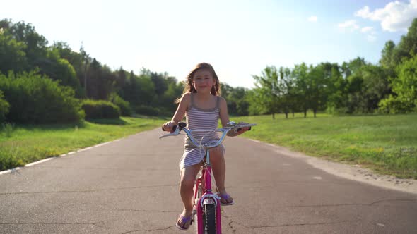 Front View Cute Little Girl Riding Bike On Driveway alt
