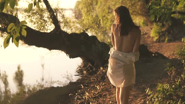 Beautiful Young Sexy Girl In A White Shirt Walks Along River Bank Among Trees alt