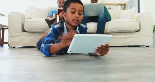 Boy using digital tablet in living room alt