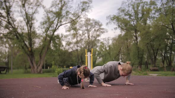  Mother and Daughter Doing Push Up Exercises on Open Air Sport Playground