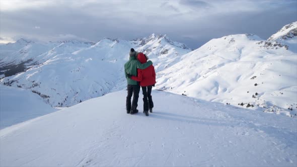 A man and woman couple standing on top of a mountain lifestyle in the snow winter alt