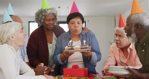 Happy senior diverse people at birthday party with cake and gifts at retirement home alt