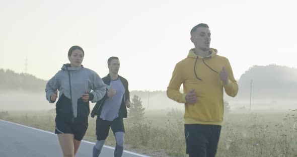 Multiethnic Group of Athletes Running Together on a Panoramic Countryside Road alt
