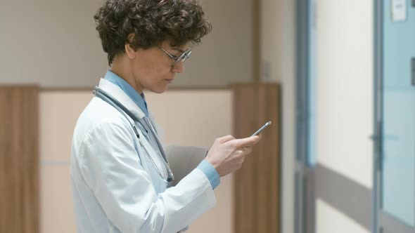 Female doctor typing on mobile phone