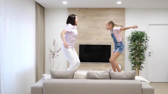 Happy Mother and Preteen Daughter Jumping on Sofa Together Baby Sitter or Mother Playing Having Fun