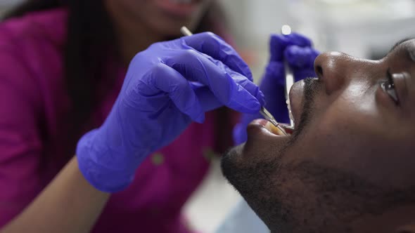 Close Up of Professional Female Dentist in Blue Protective Gloves and Pink Medical Suit Making alt
