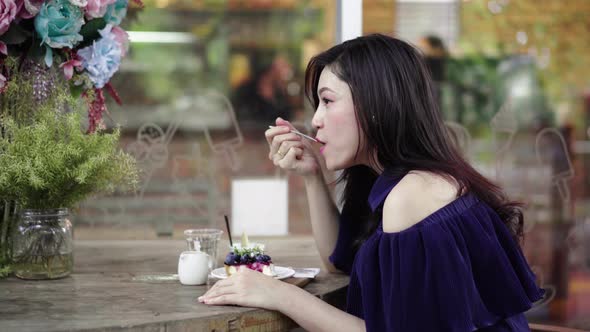 woman eating blueberry cheese cake at cafe
