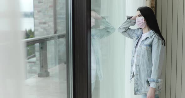 Confused Girl in Mask From Virus Comes to Glass Door Leans on It and Thinks alt