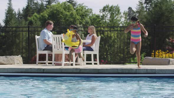 Girls jumping into backyard pool in slow motion