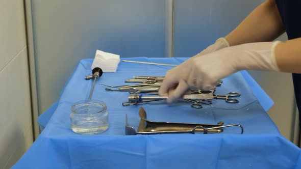 A nurse in rubber gloves prepares sterile medical instruments on for surgery. 