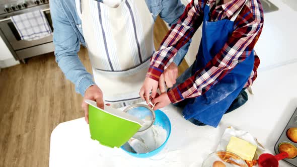 Father teaching his son how to make cupcake alt