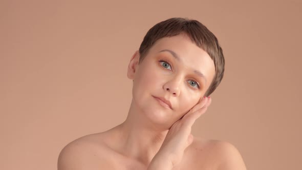 Caucasian Woman with Short Haircut and Natural Beige Makeup in Studio on Beige Background