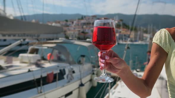 Woman Holding Glass of Wine Against Yachts at the Harbor of Poros alt