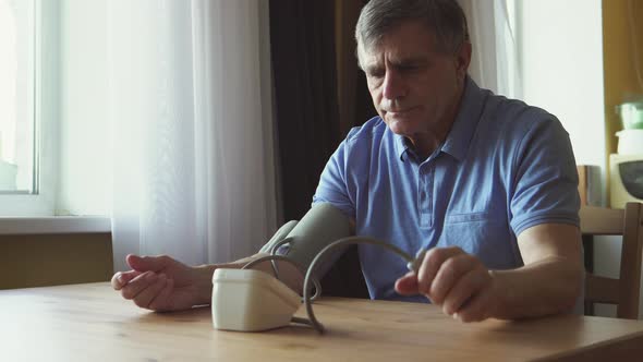 Elderly man measuring the blood pressure at the room