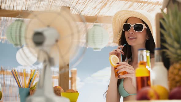 Beautiful girl having a drink at the beach bar kiosk