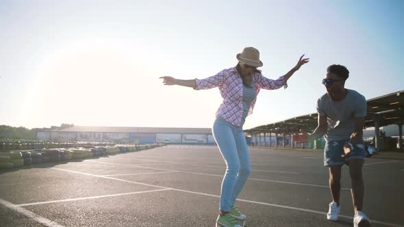 Young Attractive Mixed Race Couple Riding Skateboards and Having Fun Slow Motion alt