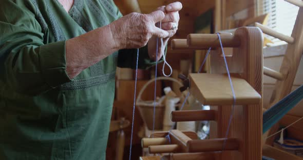 Senior woman placing woollen thread on weaving machine 4k alt