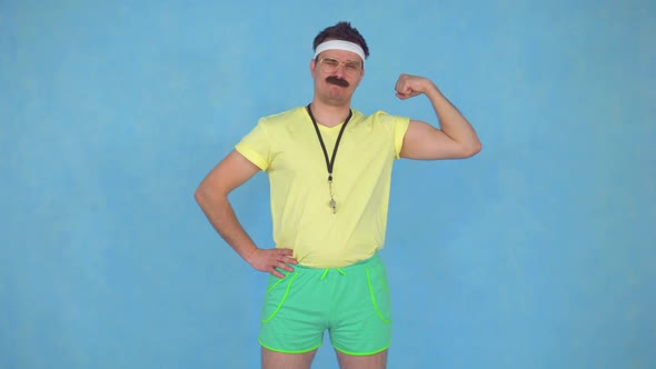 Funny Young Male Coach with a Mustache From 80's Shows His Muscles and Kisses Them alt