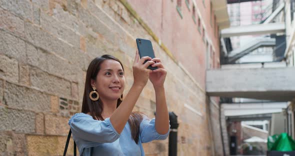 Woman tourist take photo on cellphone and visit old landmark in Hong Kong alt