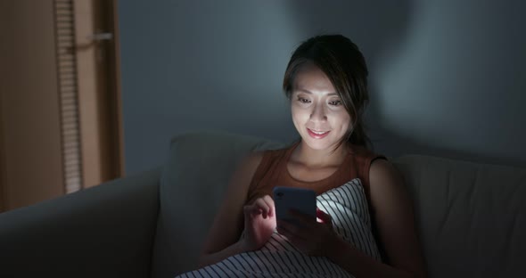 Woman use of mobile phone at home in the evening alt