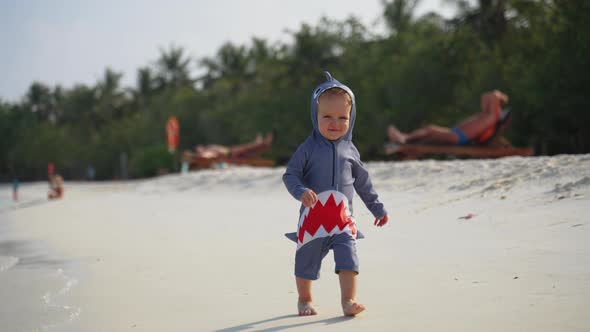 A Little Toddler in a Shark Costume Runs Towards the Camera and Laughs alt