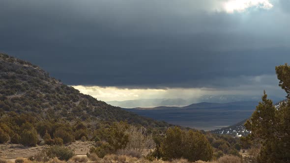 View of sun rays shining through dark clouds moving over the landscape alt