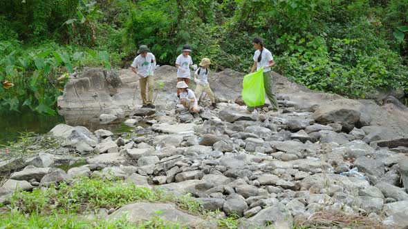 Volunteer Asian and children are collecting plastic bottles that flow through the stream