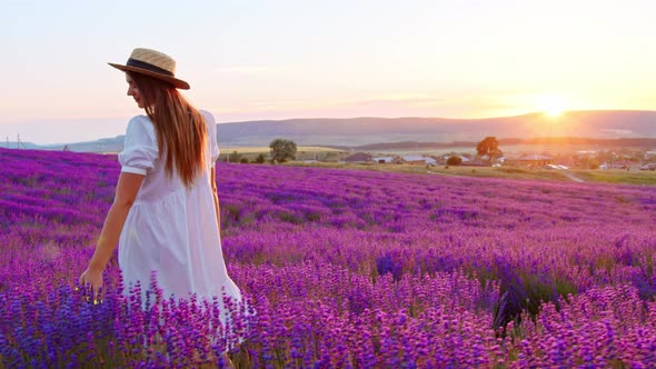 Young Woman in White Dress Walking Through a Lavender Field on Sunset