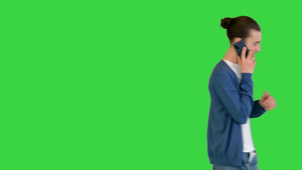 Young White Man Walks Talking on Mobile Phone on a Green Screen Chroma Key