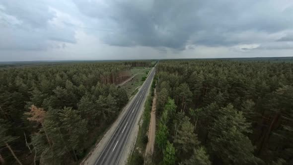 FPV Flight Over a Road in the Forest with Cut Down Areas on a Cloudy Day
