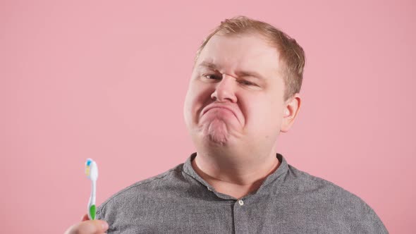 Pleasant Cheerful Man Brushing His Teeth with Vivid Emotions on Pink Background alt