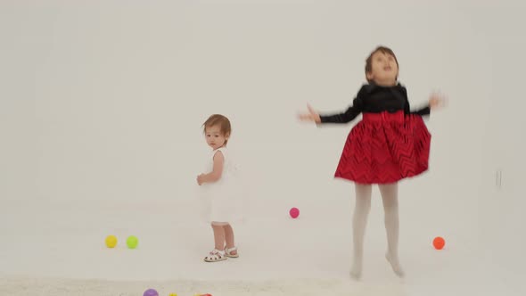 Toddler Girl Wearing Diaper and Her Sister Playing with Balls alt
