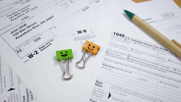 Taxes Form 1040, W-2 and W-9 with Smiles Binder Clips and Pen
