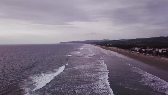 People At The Wavy Beach In Olon, Ecuador On A Cloudy Day - aerial drone alt