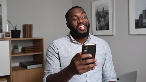 Cheerful AfricanAmerican Guy Using Smartphone alt