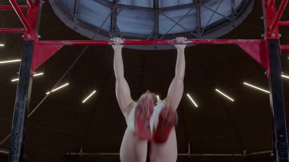 Mature Muscular Woman Taking Part in Competition Doing a Pull-up in Modern Gym