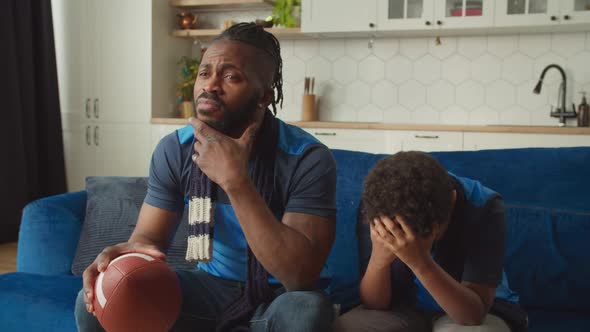 Black Father and Boy Watching American Football on Tv Disappointed By Team Loss alt