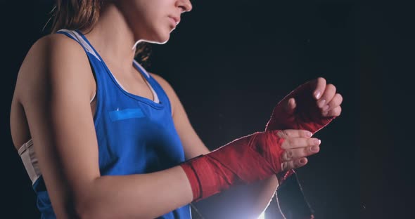 Close-up of a Beautiful Athletic Female Boxer Pulls Red Bandages on the Hands of a Female Fighter alt